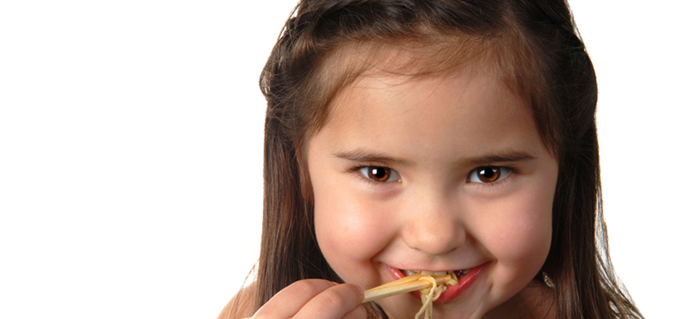 Little girl eating with chop-sticks